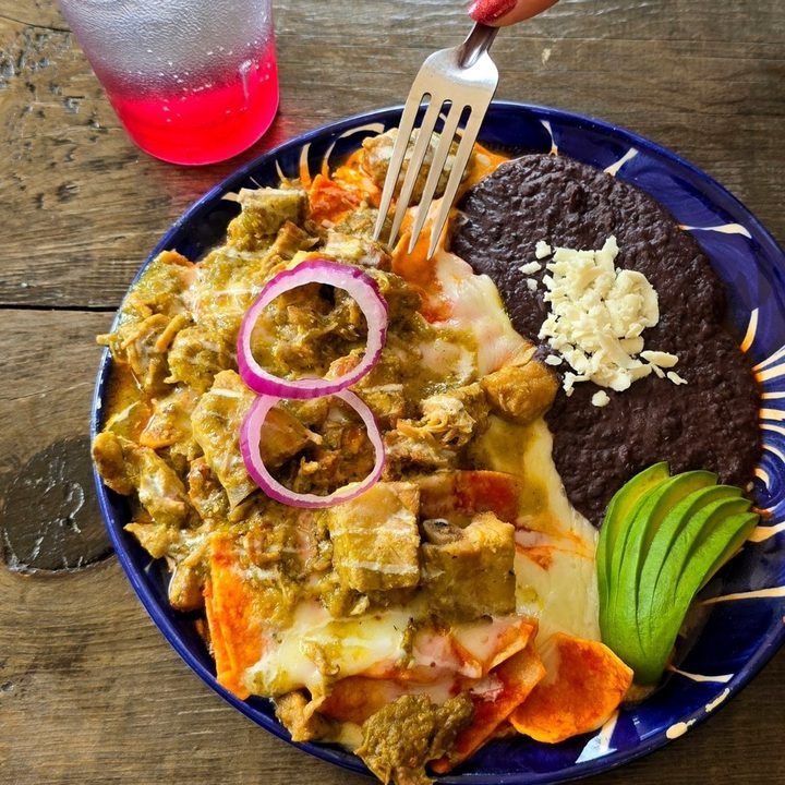 Puerco en salsa verde sobre chilaquiles, en plato de talavera
